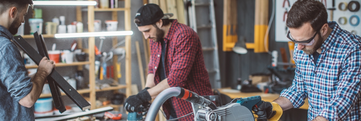 Three men working in a workshop with tools around them