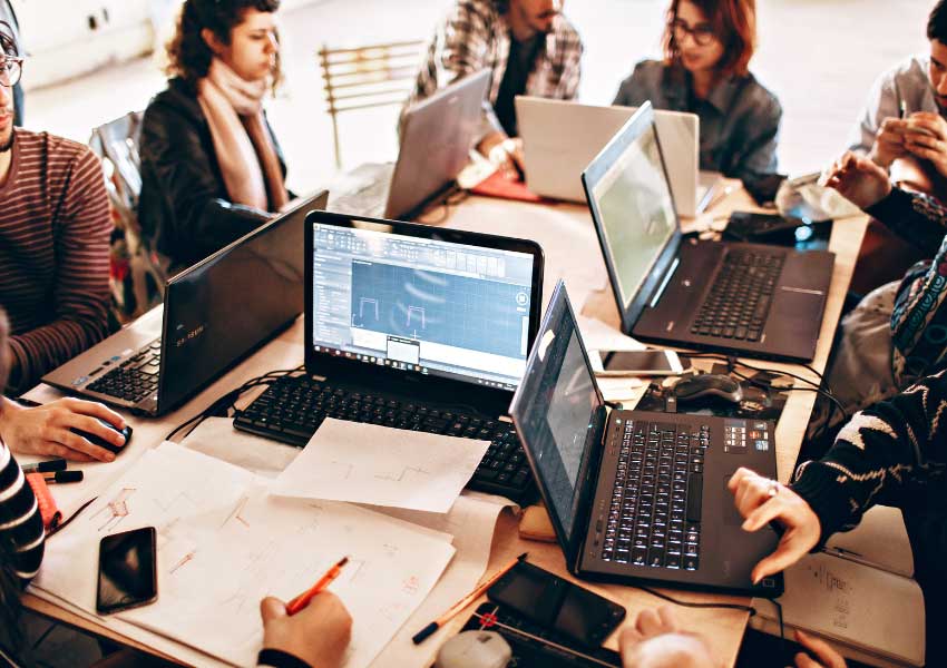 A team sitting around a table with laptops trialling new technology