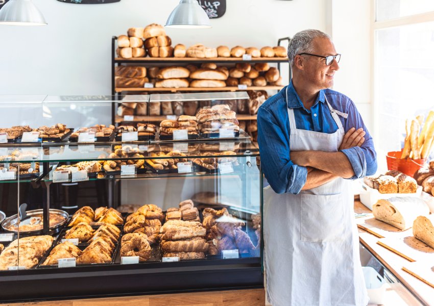 Male bakery owner looking out of shop window