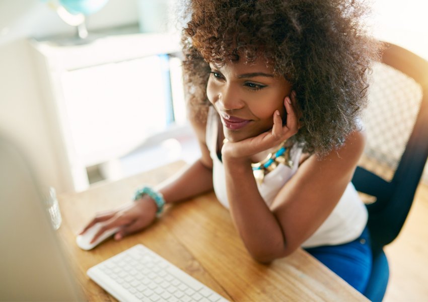 Female small business owner smiling and looking at her desktop computer