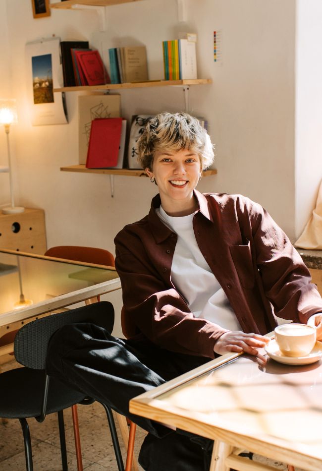 16-24 year old sitting in a sunny room and smiling at the camera