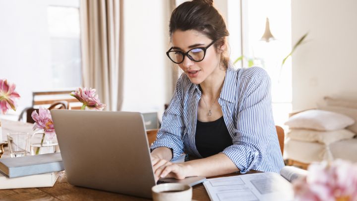 Aspiring female entrepreneur planning her new business at home on a laptop