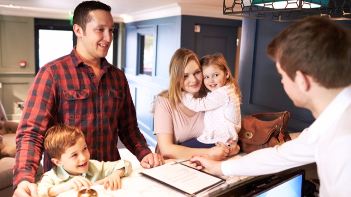 A family of four checking into a small hotel at the reception desk